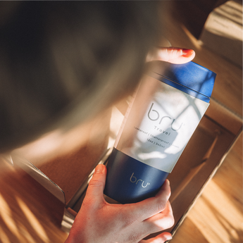 Person holding a blue bru travel mug unboxing 