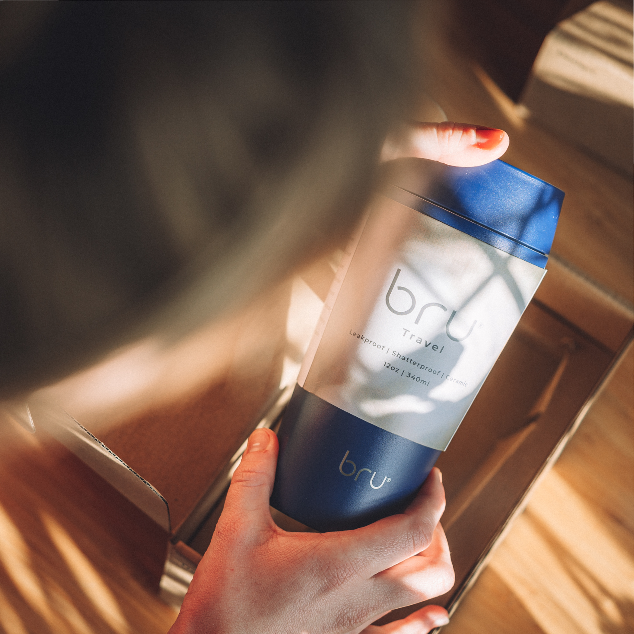 Person holding a blue bru travel mug unboxing 