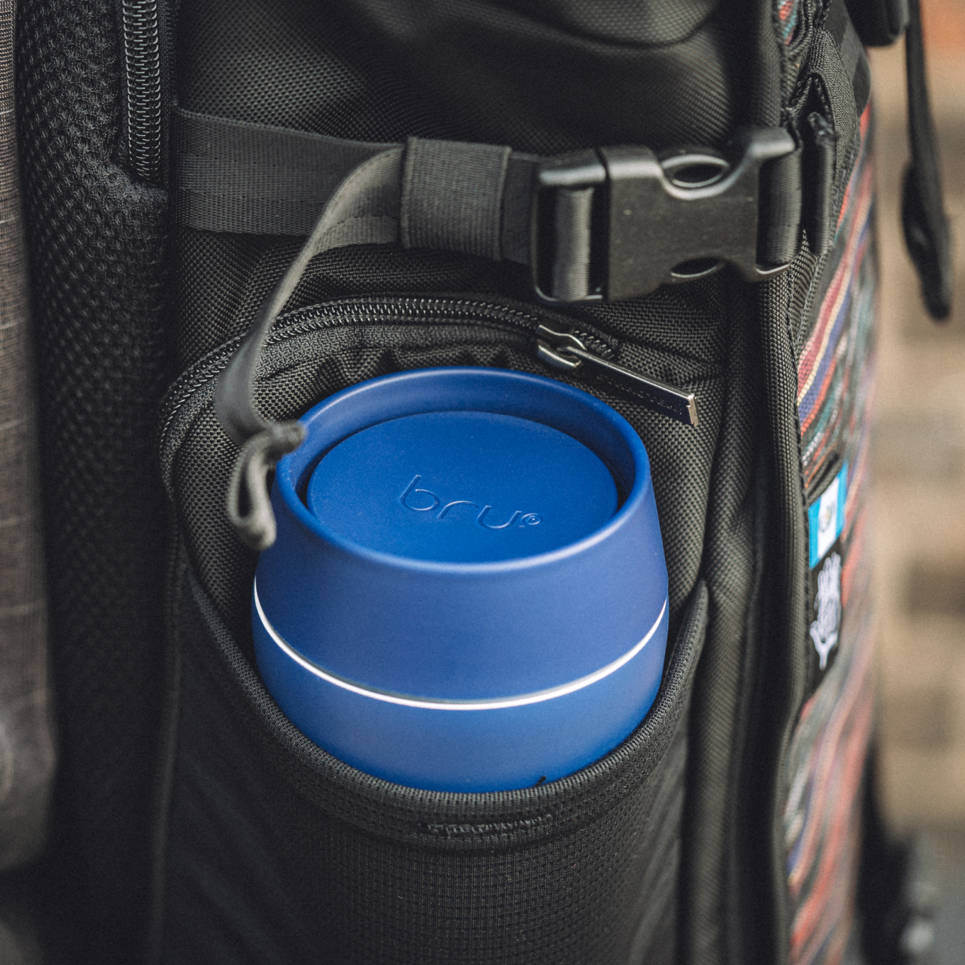 bru blue insulated travel mug in the side pocket of a backpack
