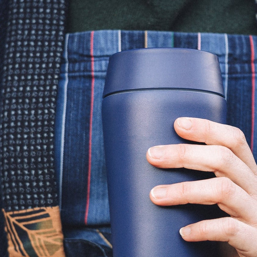 Bru-Cups ceramic-lined travel mug, blue, being held by a hipster wearing an apron.