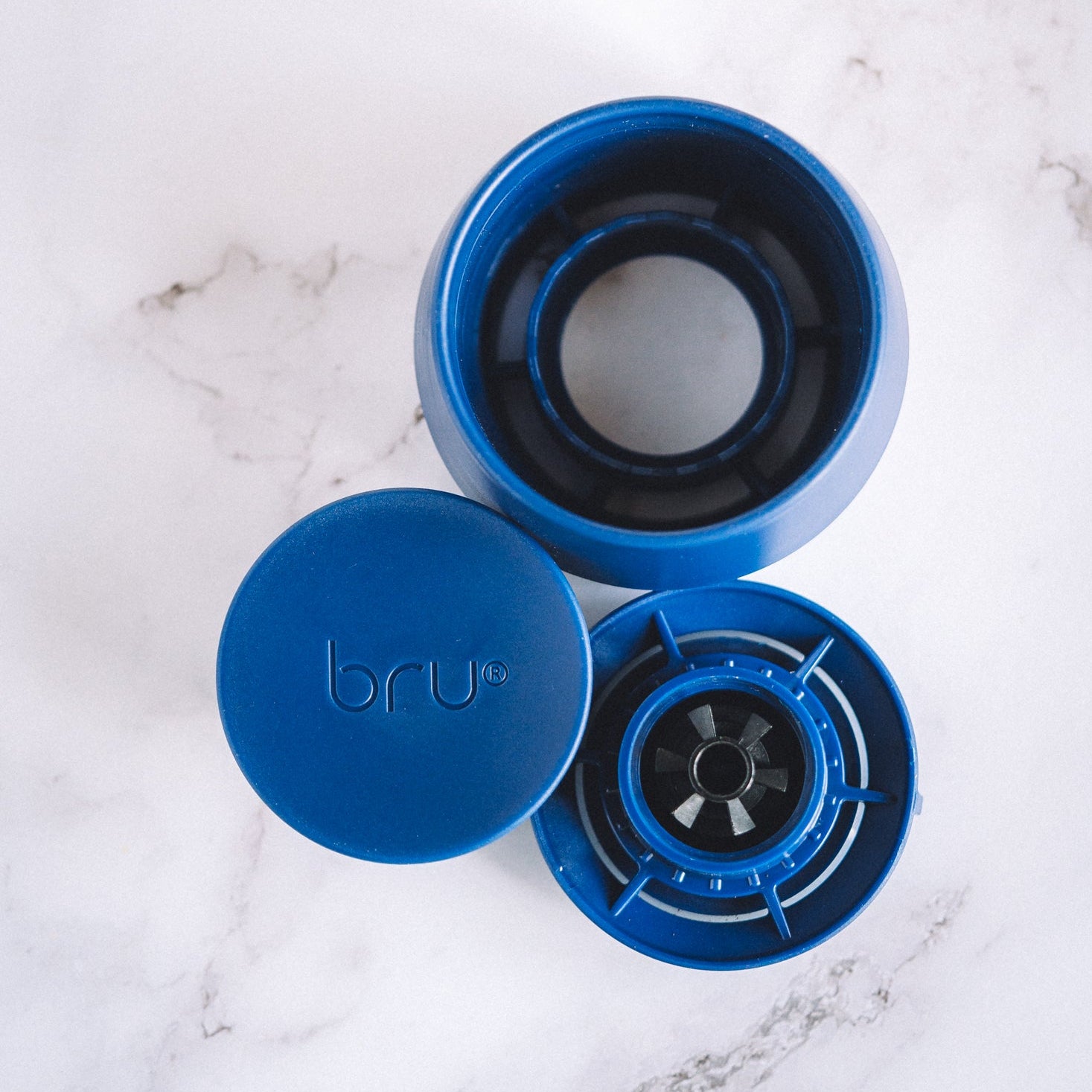 bru ceramic travel mug lid split into three parts on a marble surface